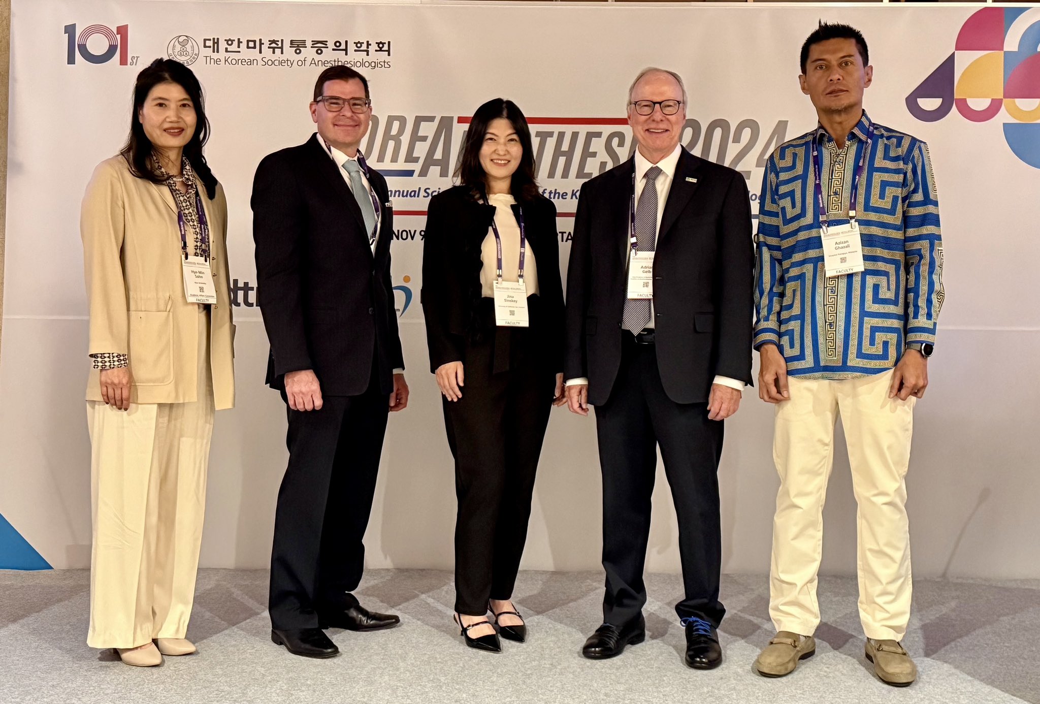 Five people posed together sanding in front of a large conference banner