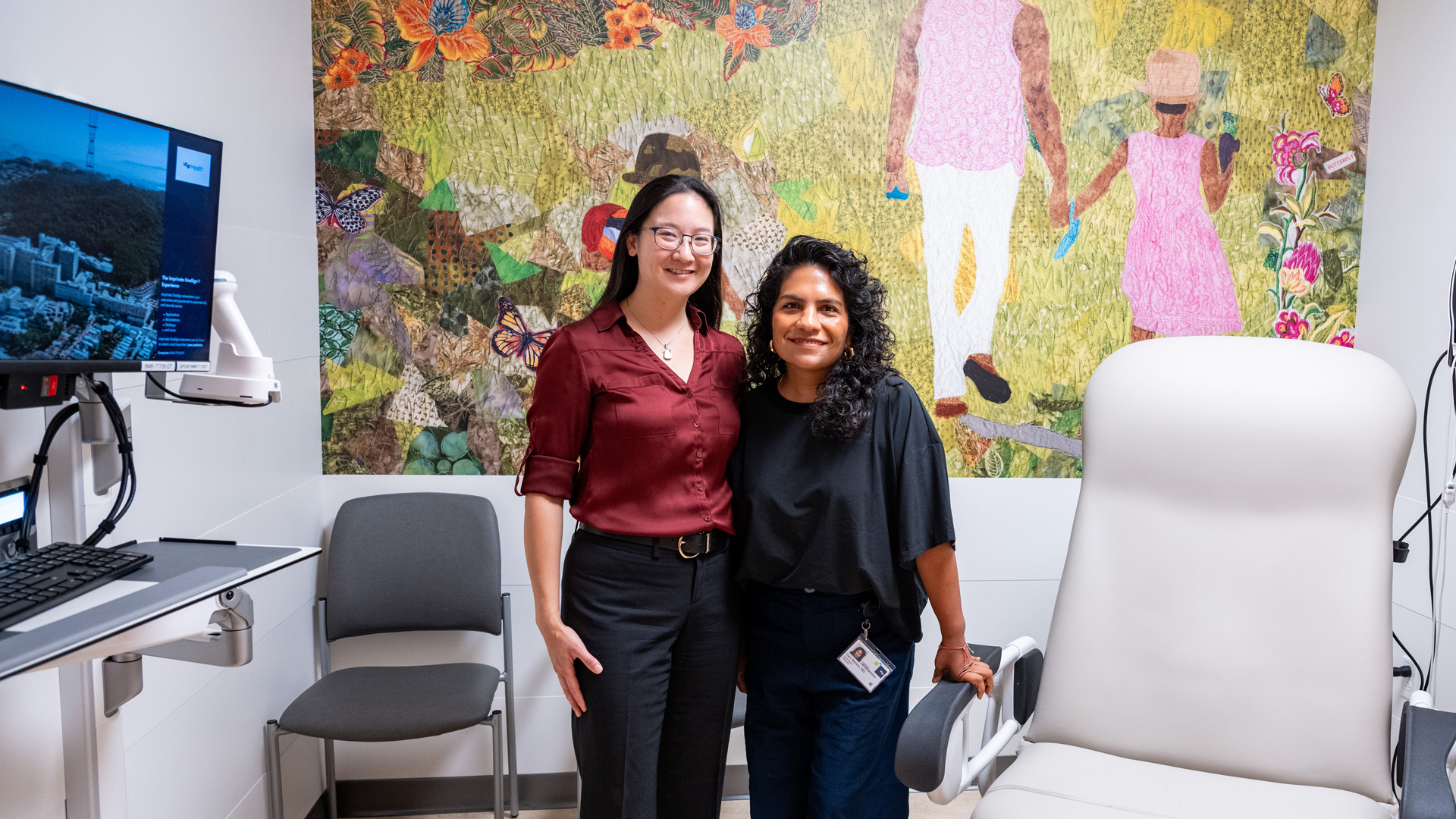 Two woman standing together in a clinical consultation room featuring a wall sized mural