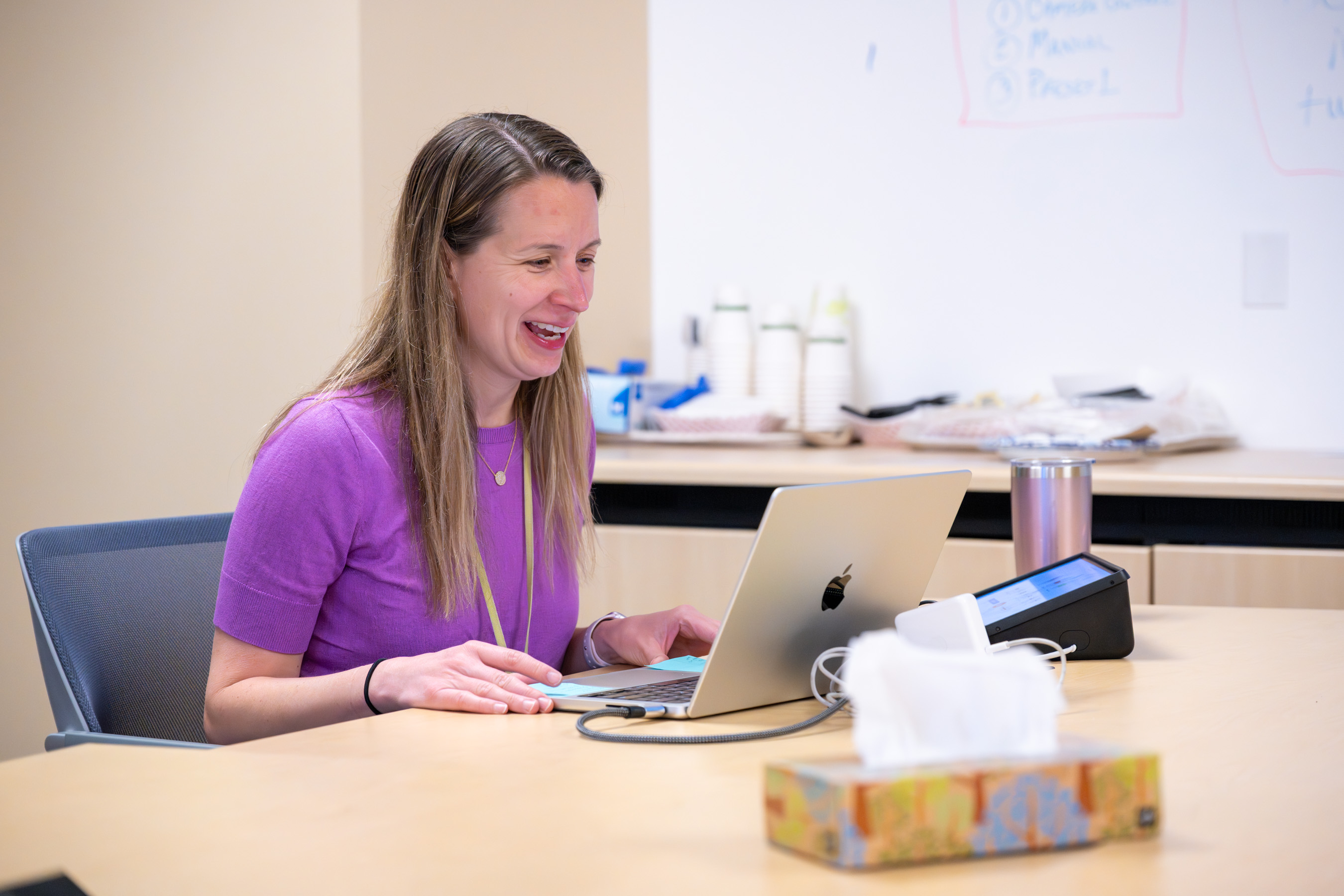 Dr. Ferschl seated at a conference table speaking with someone on Zoom via a laptop on the table in front of her.