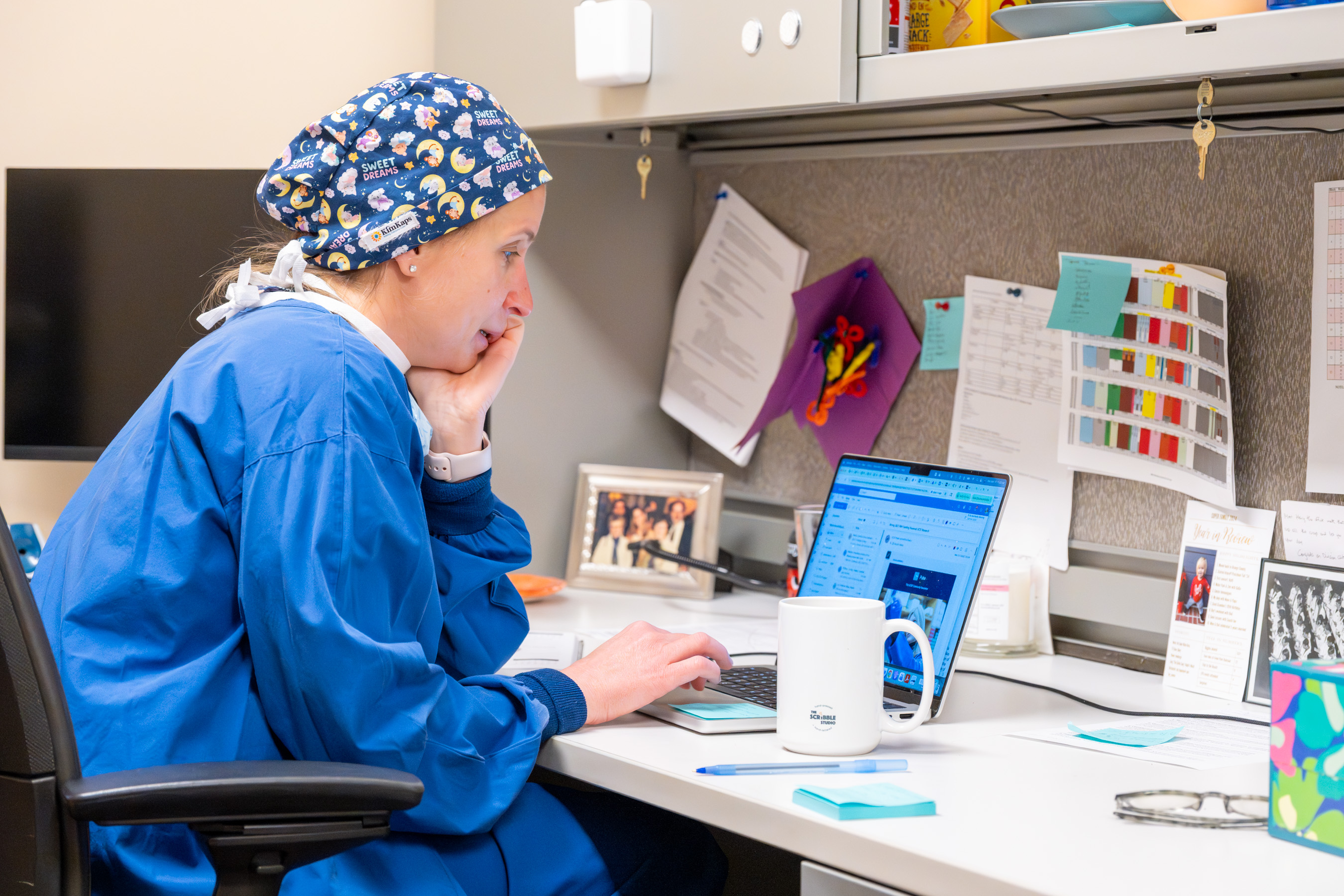 Dr. Ferschl seated at a desk looking at her laptop in her office.