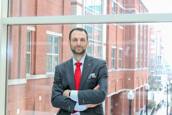 man in a suit and red tie in front of a building.