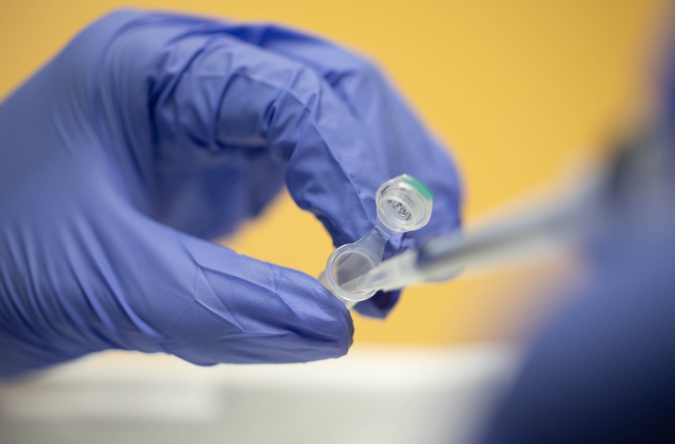 a gloved hand holding a pipette.