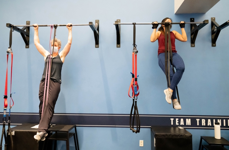 Jessie Dubreuil, left, and Sammi Tam do chin-ups while suspended by bands, in a circuit weight training exercise class at the Bakar Fitness Center.