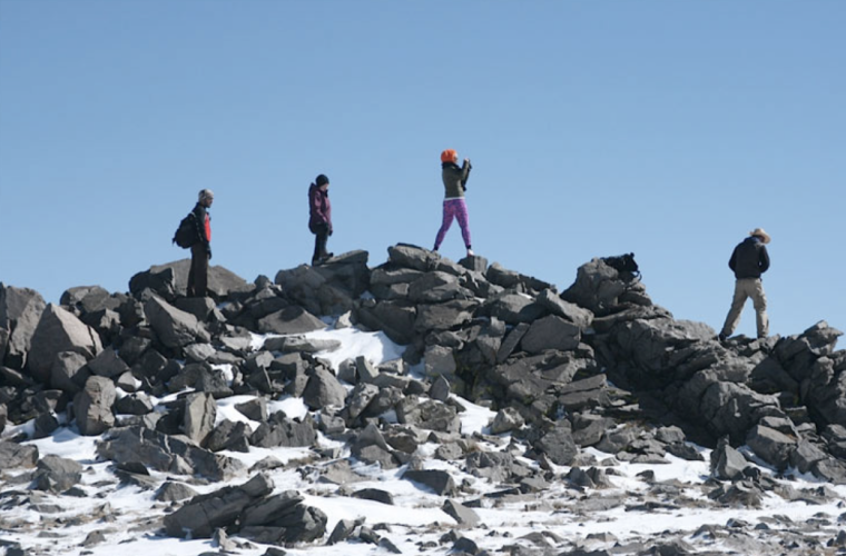 people walking on top of snowy rocks