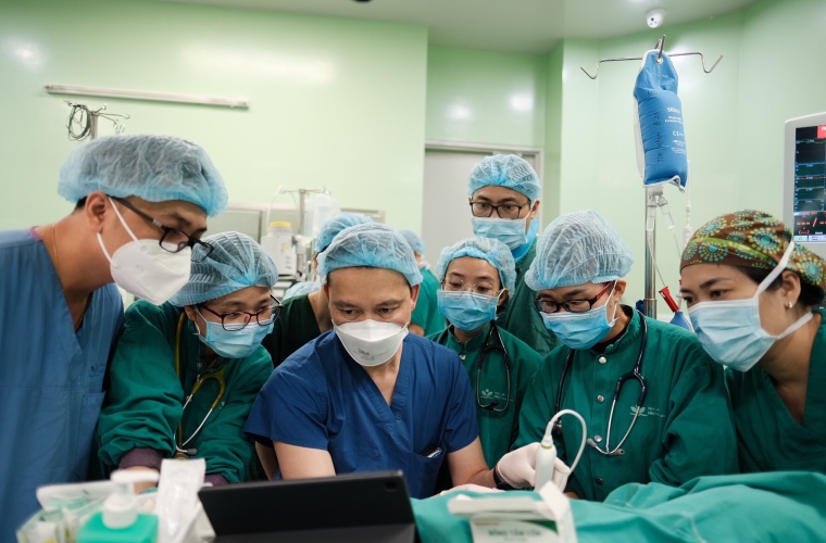 group of doctors in an OR looking at a laptop