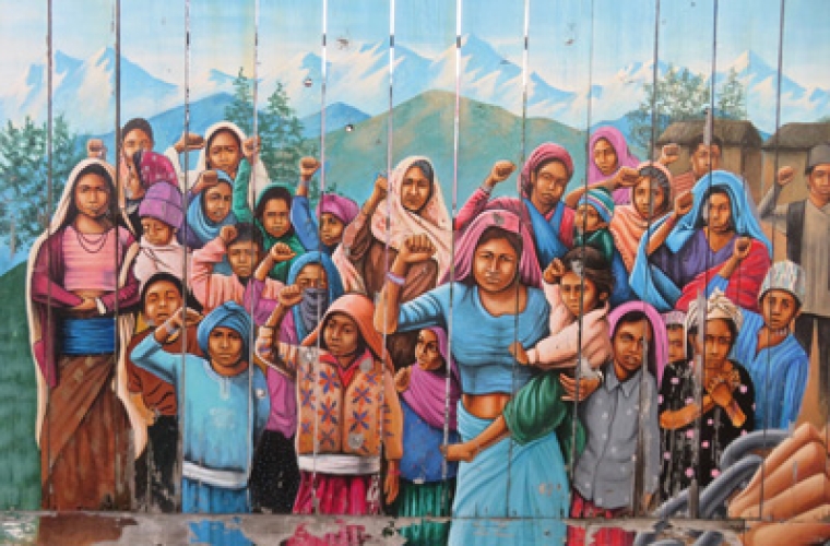A colorful mural painted on a fence of a group of women of all ages showing solidarity.