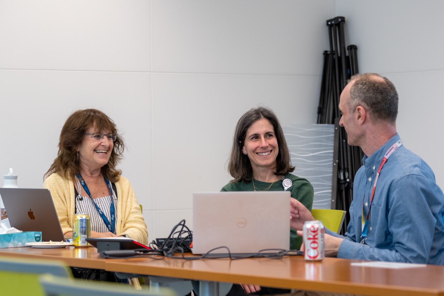 Three people sitting at a table engaged in conversation and smiling.