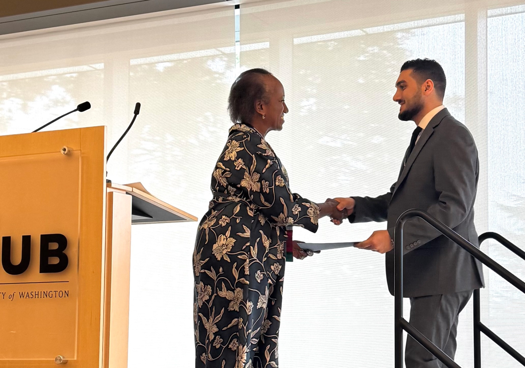 Two people shaking hands near a lecturn.