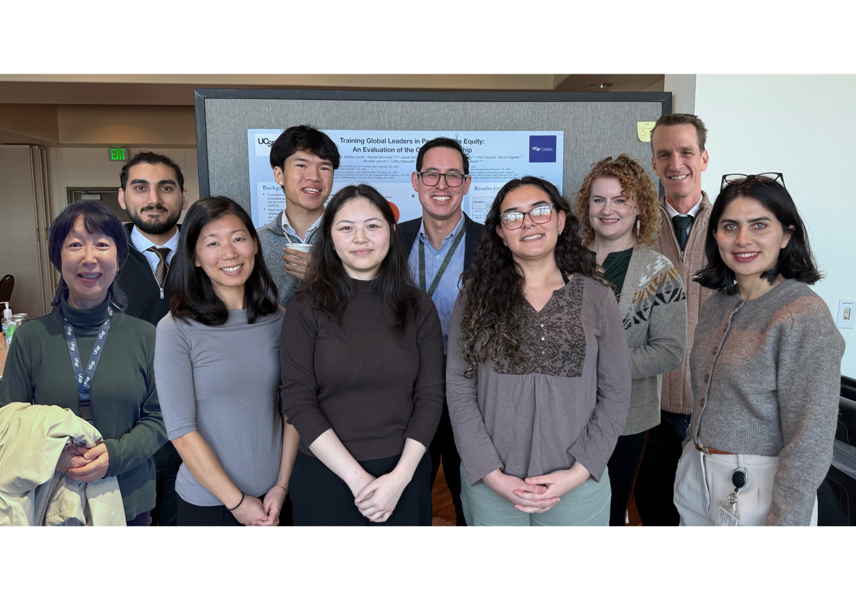 A group of ten people standing together in front of a scientific paper.