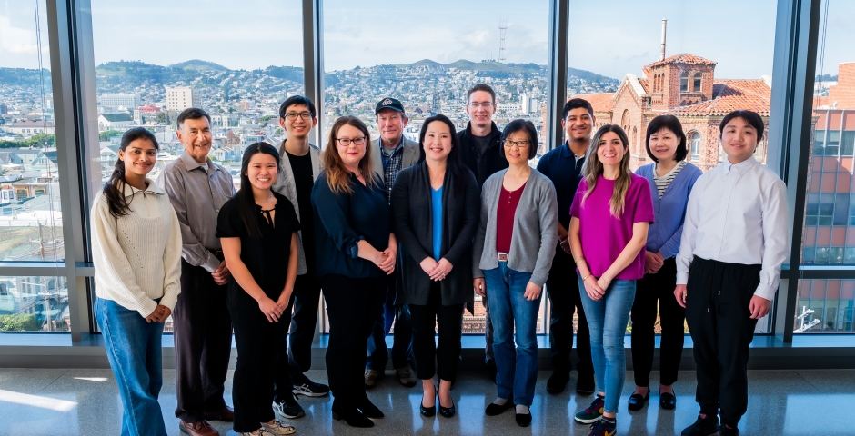 group of people standing in front of a window, overlooking sf.