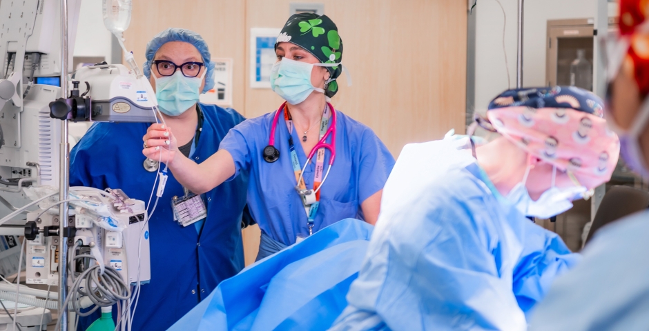 People wearing scrubs and working with medical equipment in a clinical setting.
