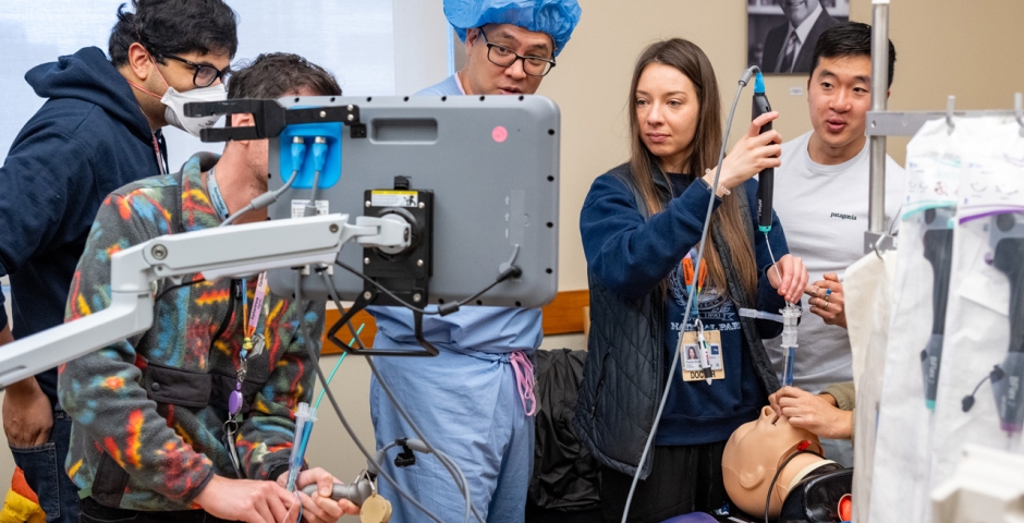 A group of trainees interacting with medical equipment in a training room setting.