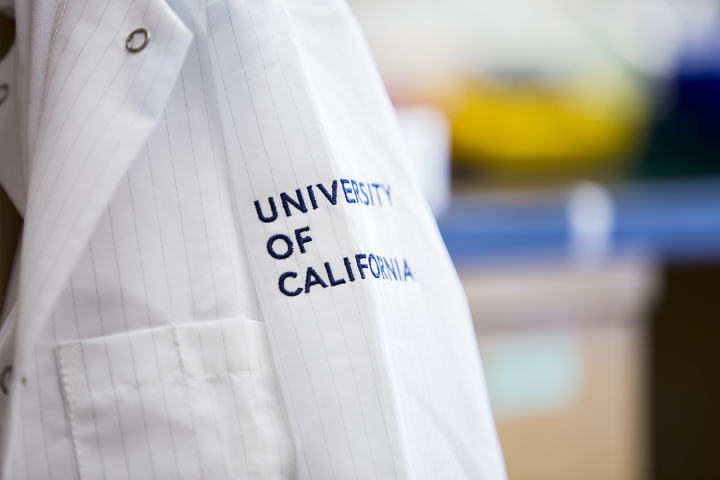 A white lab coat with blue writing that says University of California.