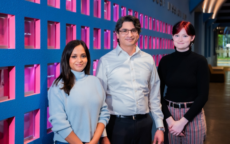 three people looking into the camera, with blue and pink background.