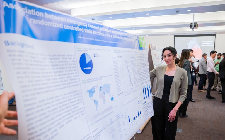 woman stands next to a research poster