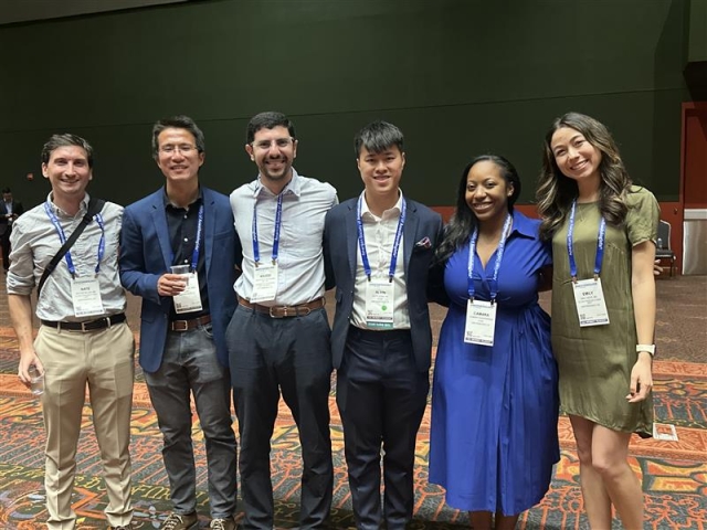 Six people standing arm in arm together wearing conference nametags.