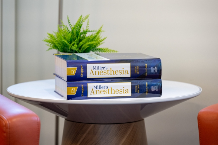 Both volumes of Miller's Anesthesia textbook on a table with a small green plant.