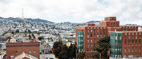 view of older Zuckerberg San Francisco General Hospital brick buildings, with SF streets and buildings in background