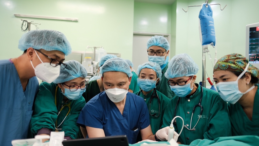 group of doctors in an OR looking at a laptop