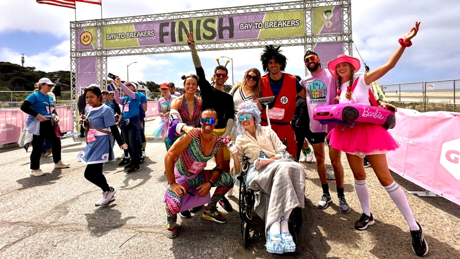 A group of people in colorful costumes celebrating at the finish line of the Bay to Breakers race