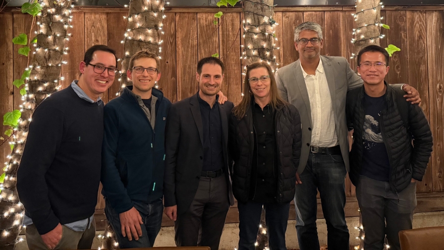 Six people standing together with string lights in the background.