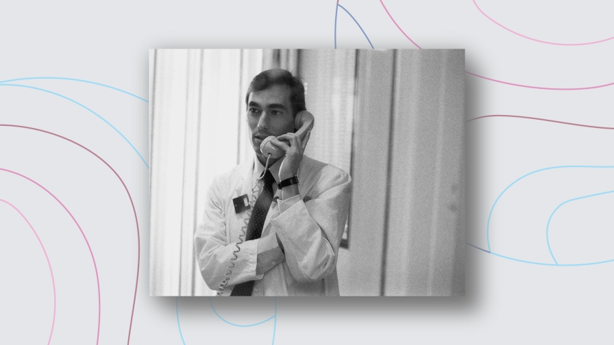 Man wearing a lab coat speaking on the phone in black and white.