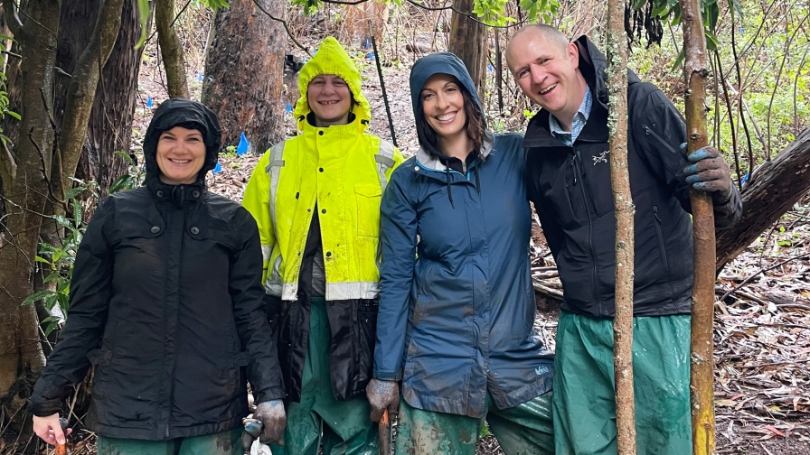 Four people in rain gear smiling together outside in the rain.