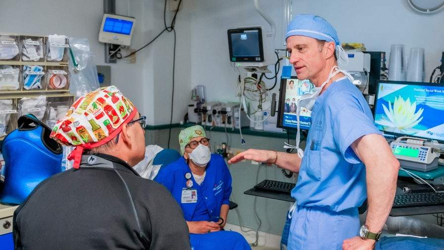 Three men wearing scrubs in a clinical setting.