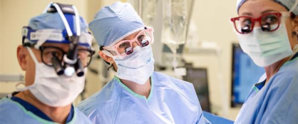 Neil Cambronero, MD, left, assistant professor of Clinical Surgery, Paula Price, PA, center, physician assistant, and Reia Zimmer, RN, perform a cardiac surgery,