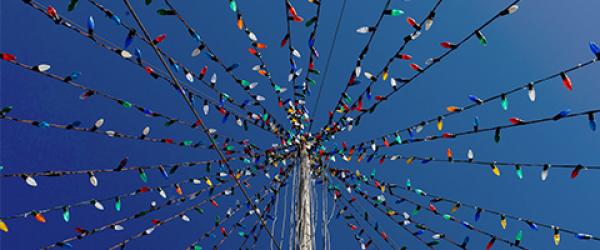 multicolored strings of lights on a roof with blue sky above