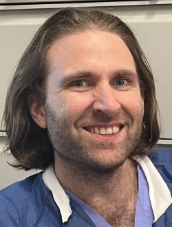 a man in scrubs smiling at the camera.