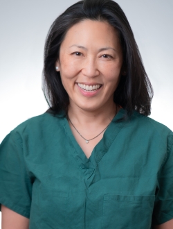 Woman in green scrubs smiling.