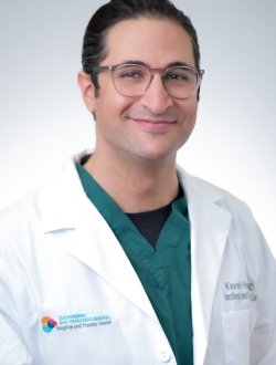 man in green scrubs and white lab coat and glasses.