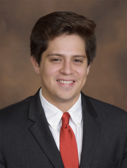 Man wearing black jacket, white collard shirt and red tie. 