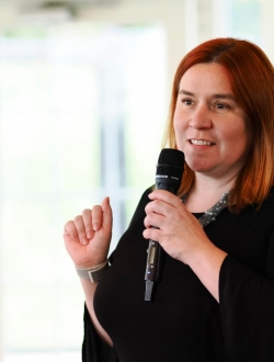 woman in all black talking into a microphone.