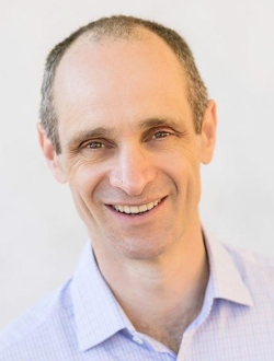 Smiling man with short brown hair in a light blue shirt