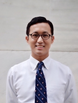 Person with short dark hair, glasses and a tie