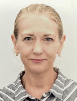 Person with blond hair pulled back wearing a striped white and grey shirt