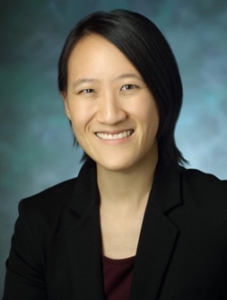 Smiling woman with shoulder length black hair wearing a dark jacket