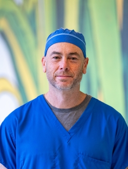 Man in blue scrubs with a green background