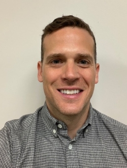 Smiling man with short dark hair and a grey shirt