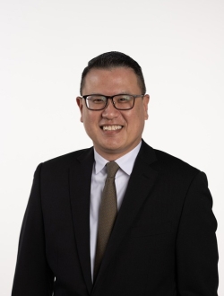 Smiling man with glasses wearing a dark suit and tie