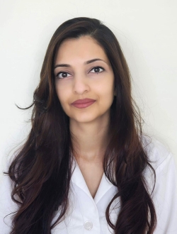 Woman with long dark hair wearing a white jacket.