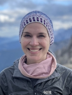 Woman smiling with clouds and mountains in the background