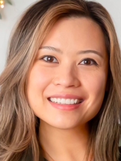 Woman with long brown hair smiling and looking straight ahead