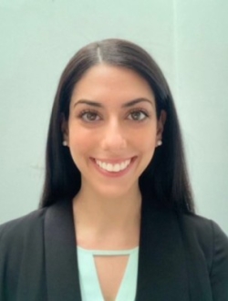 Smiling woman with long black hair wearing a black blazer over a mint green top.