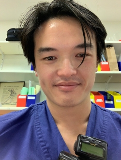 Man with black hair wearing scrubs.