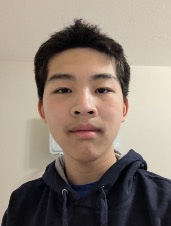 Man with short black hair wearing a dark hoodie.