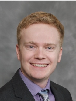 Smiling man with red hair wearing a suit and tie.