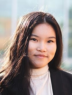 Woman with long dark brown hair wearing a dark brown jacket.